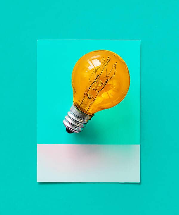 Orange light bulb on a teal background